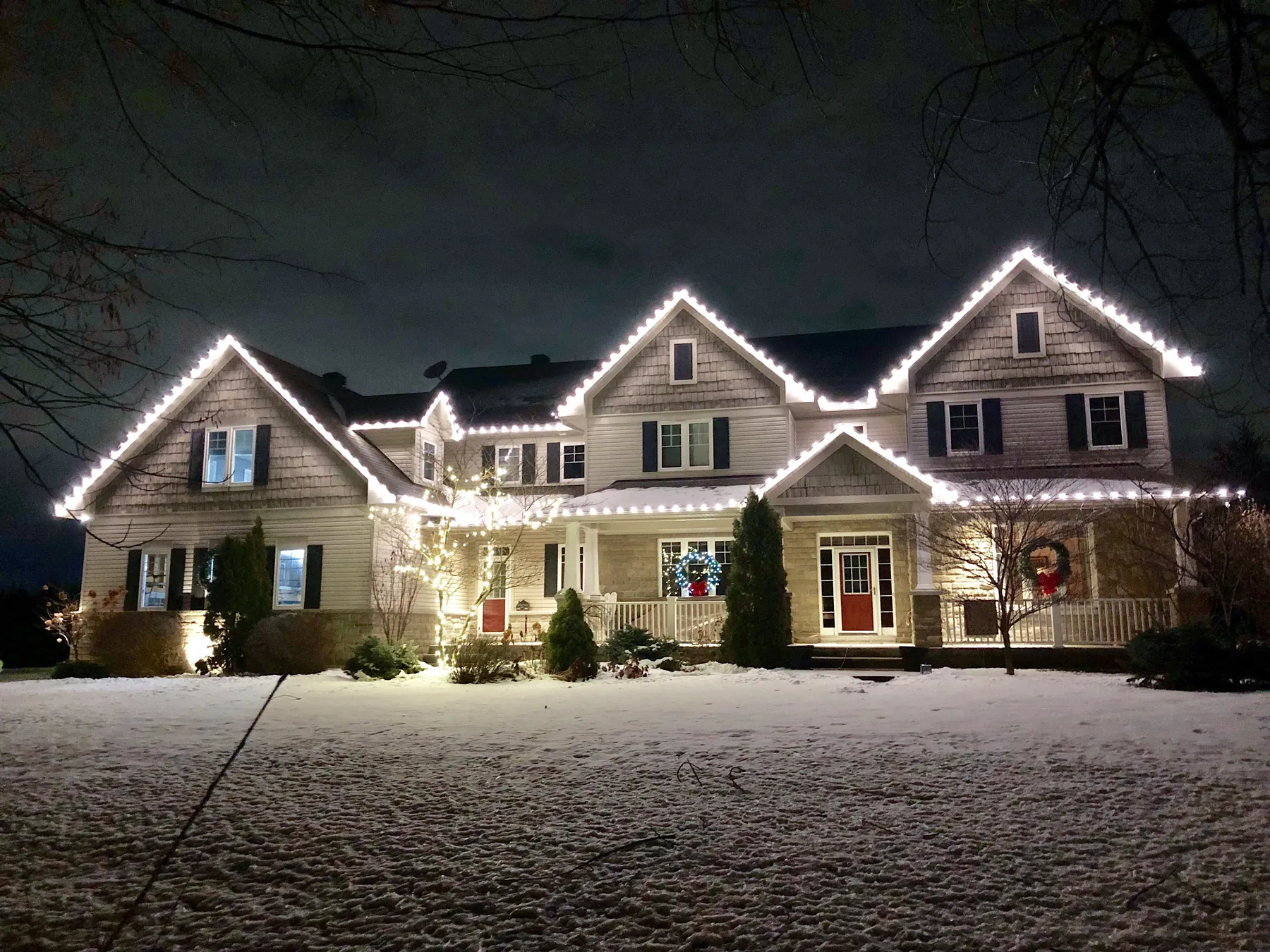 Home outlined in warm white holiday lights after dark